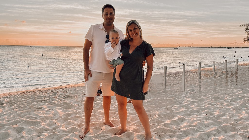 Family of three standing on Seven Mile Beach in Grand Cayman