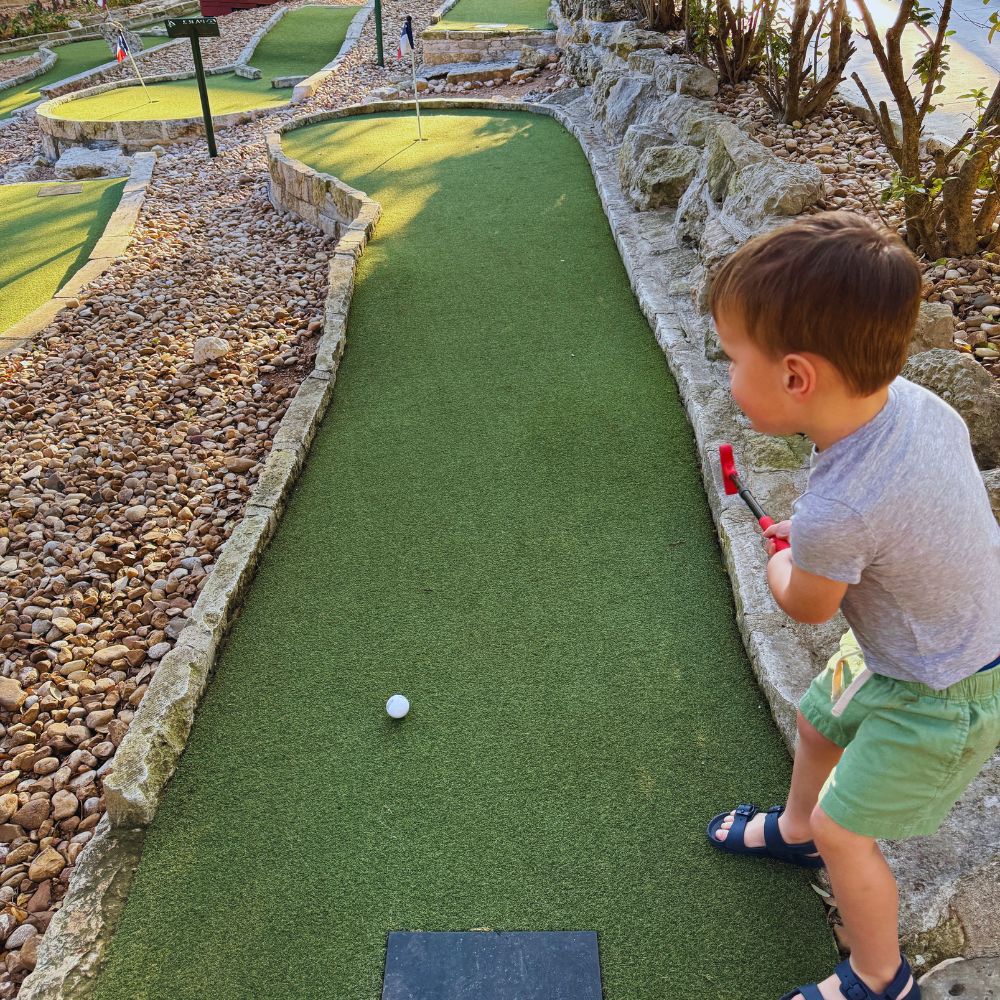 Omni Barton Springs mini golf kid swinging golf club