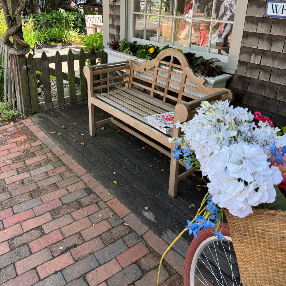 Bench against gray shingle building with bike and flower basket in Nantucket Massachusetts