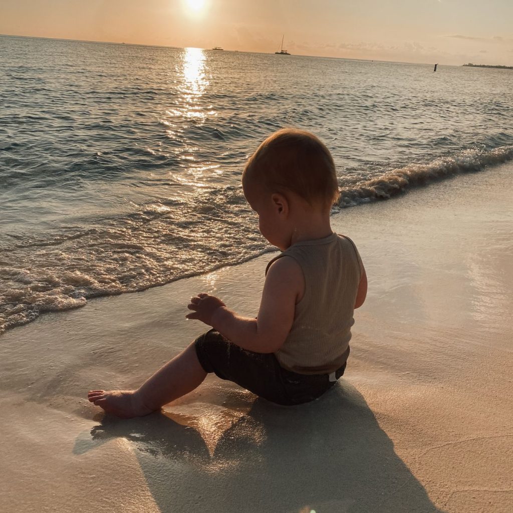 baby sitting at the shore at sunset in Grand Cayman